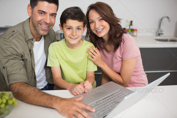 Portrait of a smiling couple with young son using laptop at home (Misc) Photo Download