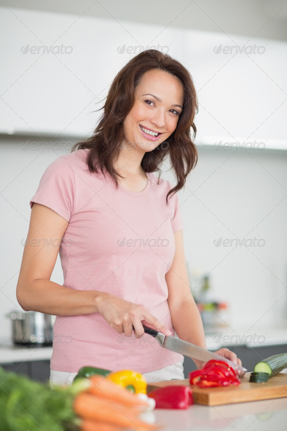 Portrait of a smiling young woman chopping vegetables in the kitchen at home (Misc) Photo Download