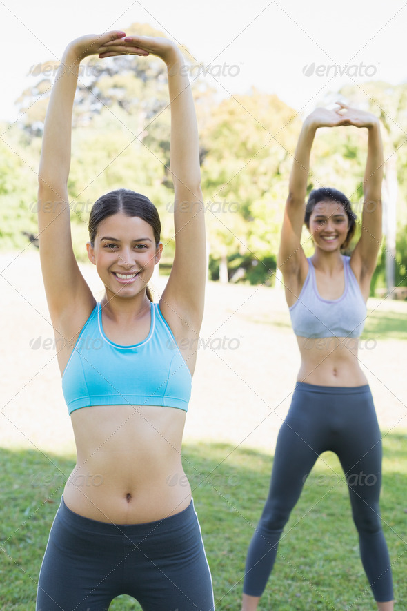 Portrait of smiling sporty women doing stretching exercise in park (Misc) Photo Download