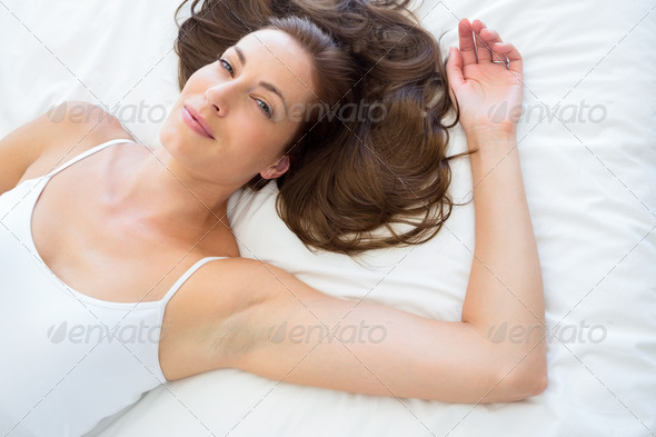 Portrait of a pretty smiling young woman lying in bed at home (Misc) Photo Download