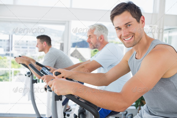 Portrait of handsome man on exercise bike in fitness club (Misc) Photo Download