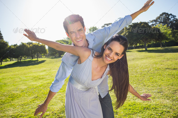 Portrait of a happy young couple with arms outstretched at the park (Misc) Photo Download