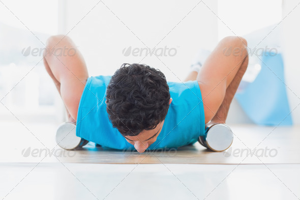 Determined young man doing push ups with dumbbells in the fitness studio (Misc) Photo Download