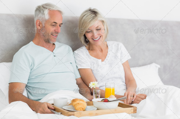 Happy mature couple having breakfast in bed at home (Misc) Photo Download