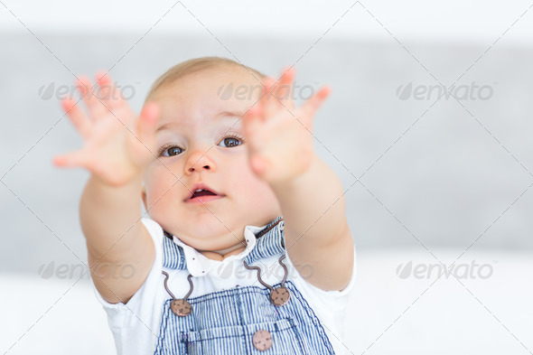 Closeup portrait of a cute baby holding out his hands over blurred background (Misc) Photo Download