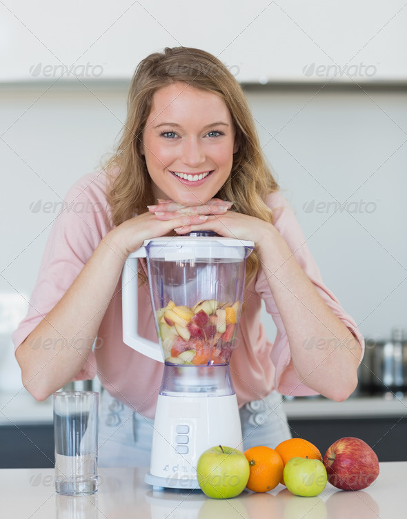 Portrait of happy young woman preparing mix fruit juice in liquidizer at kitchen counter (Misc) Photo Download