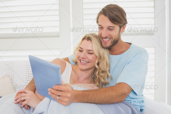 Young couple using tablet pc on the couch at home in the living room (Misc) Photo Download