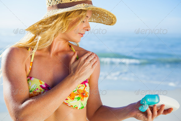 Gorgeous blonde in bikini applying suncream on the beach on a sunny day (Misc) Photo Download