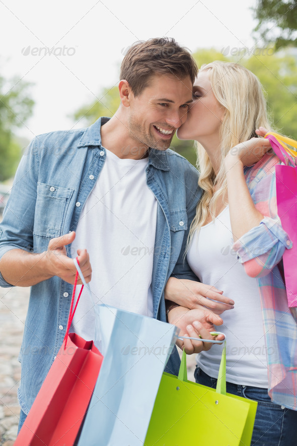 Hip young couple holding shopping bags on a sunny day in the city (Misc) Photo Download