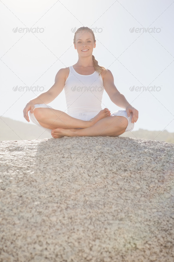 Smiling woman sitting in lotus pose on beach on a sunny day (Misc) Photo Download