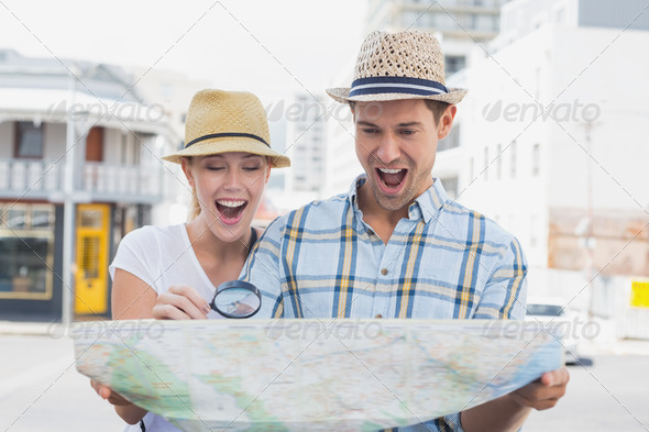 Young tourist couple consulting the map with magnifying glass on a sunny day in the city (Misc) Photo Download