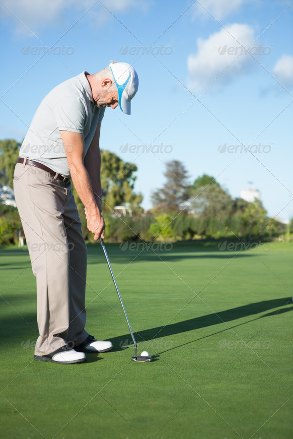 Handsome golfer putting ball on the green on a sunny day at the golf course (Misc) Photo Download