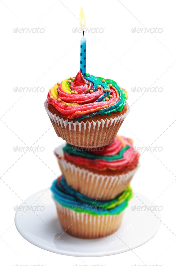 Pyramid of three colorful cupcakes with a burning candle