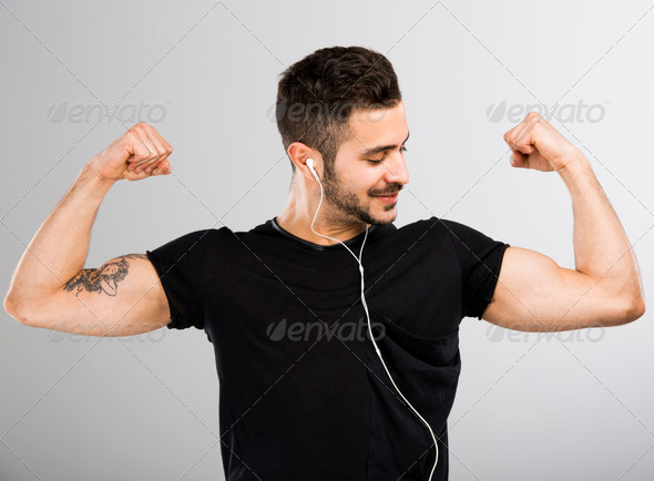 Man listen music and looking his muscles