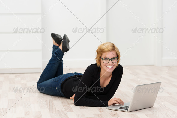 Smiling young woman lying on the floor working