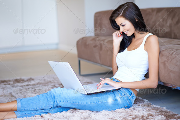 Woman smiling as she surfs the net on a laptop