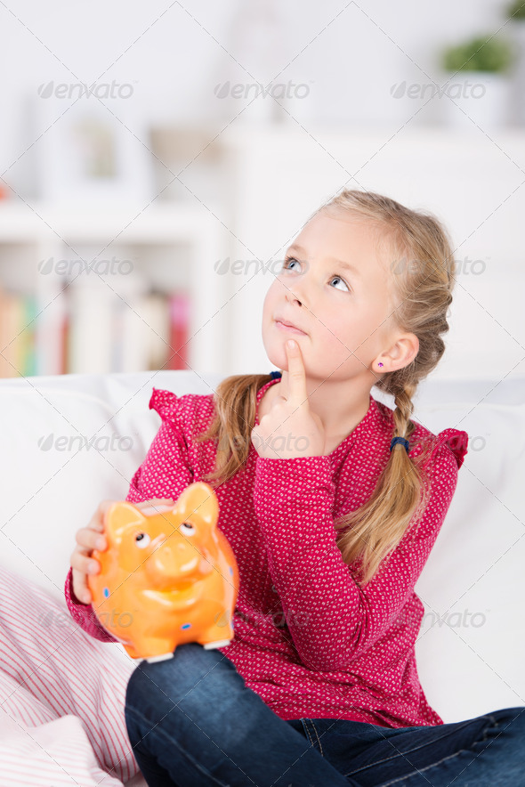 thoughtful girl with piggy bank