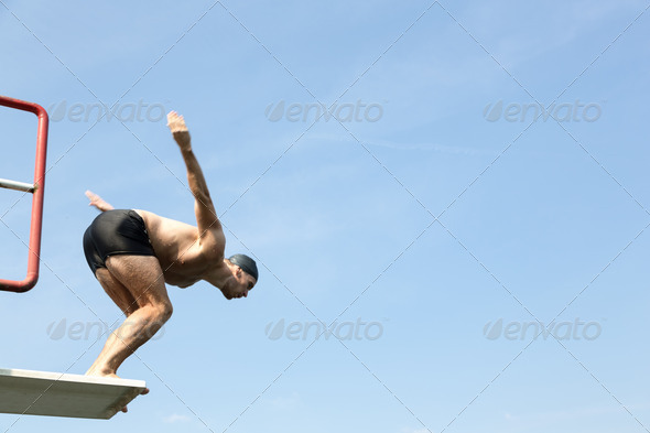 Man jumping off diving board at swimming pool