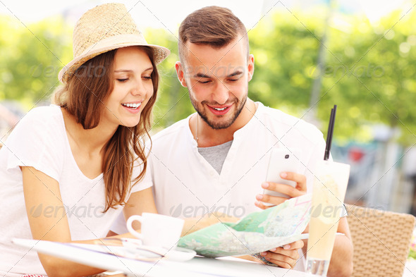 Happy tourists with a map in a cafe