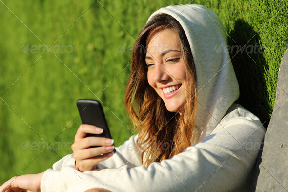 Modern teenager girl using a smart phone in a park