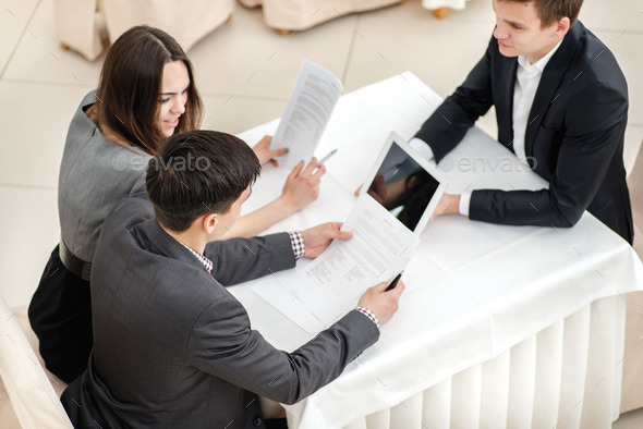 Checking documents! Three young businessman sitting at a table i