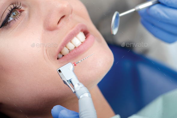 Dental drill near the women27;s smiles. Dentist makes the process