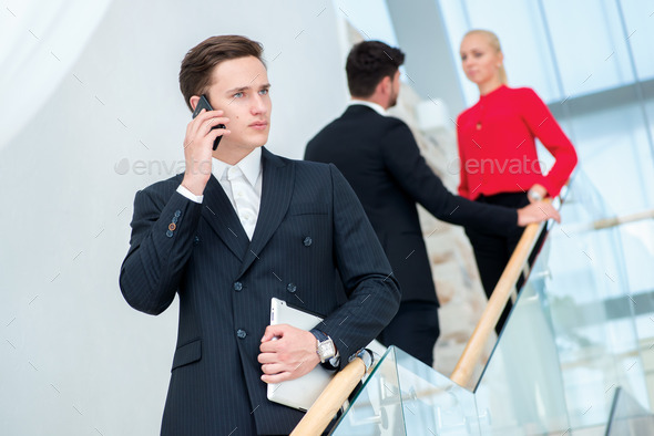 Businessman talking on the phone. Young businessman standing on