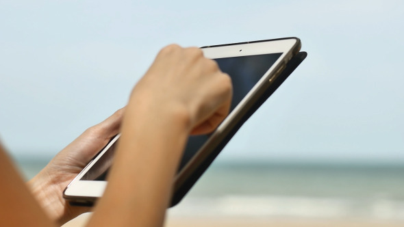 Woman Using a Tablet On Beach Woman Using a Tablet On Beach