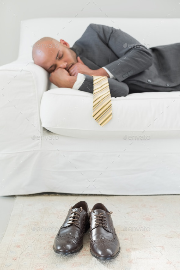Elegant young businessman sleeping on sofa at home