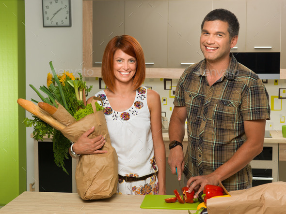happy couplestanding in kitchen and cooking