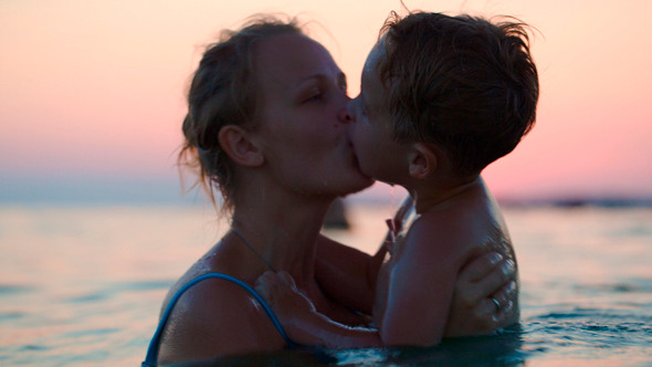 Mother And Son Having Fun In Sea At Sunset Mother And Son Having Fun In Sea At Sunset