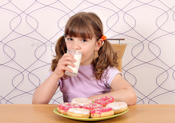 little girl with sweet donuts and milk breakfast