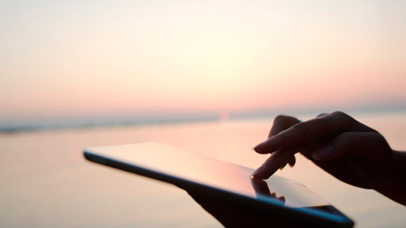 Female Hands Typing On Tablet Pc By Sea At Sunset Female Hands Typing On Tablet Pc By Sea At Sunset