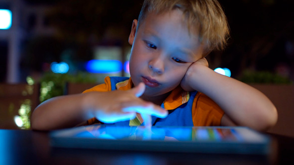 Bored Little Boy Using Pad In Cafe Bored Little Boy Using Pad In Cafe