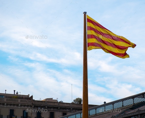 Catalan flag on a rooftop against blue sky in Barcelona, Spain (Misc) Photo Download