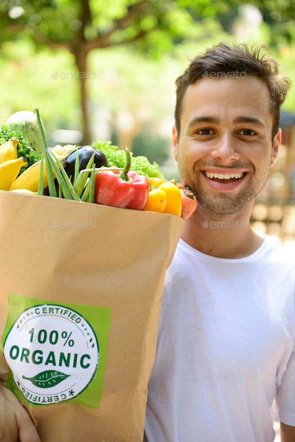 Happy man carrying bag of organic vegetables.