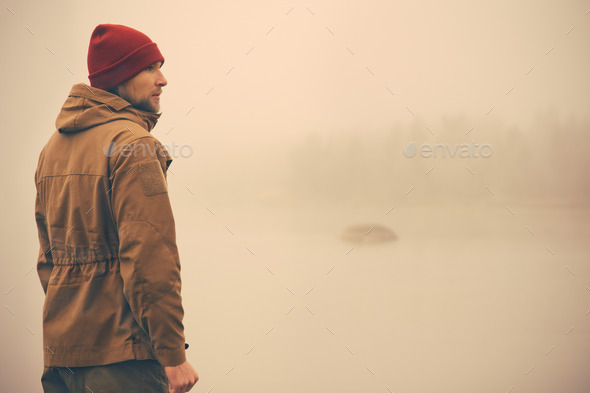 Young Man standing alone outdoor with foggy scandinavian nature on background