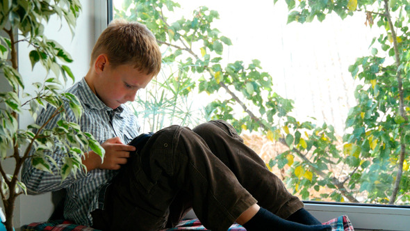 Boy Sitting By A Window Using His Tablet 2 Boy Sitting By A Window Using His Tablet 2