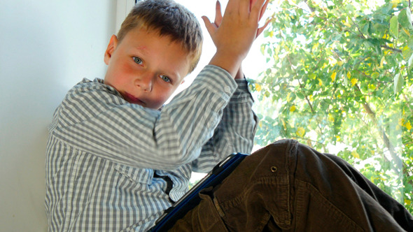 Boy Sitting By A Window Using His Tablet 5 Boy Sitting By A Window Using His Tablet 5
