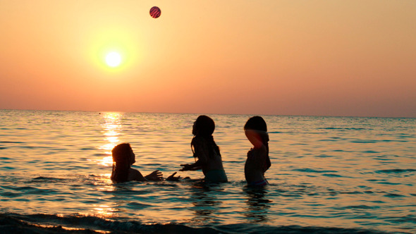 Girls Playing With Ball In Sea At Sunset Girls Playing With Ball In Sea At Sunset