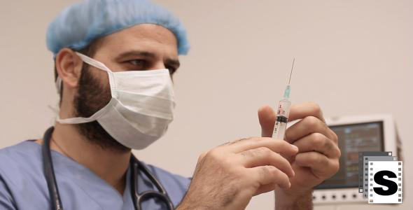 Male Surgeon Checks Medical Syringe Male Surgeon Checks Medical Syringe