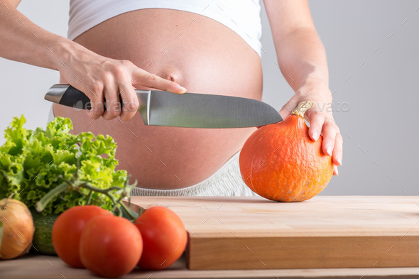 Pregnant woman slicing fresh vegetables