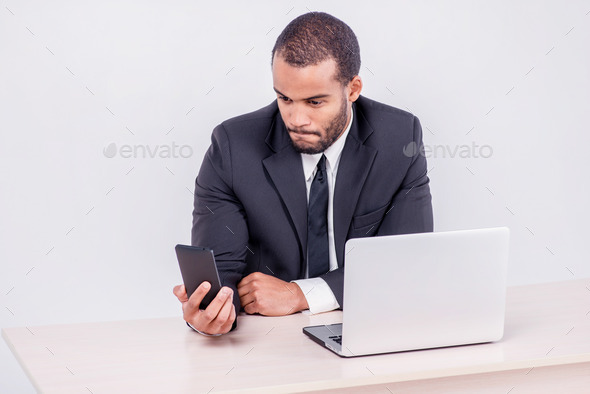 Customer call. Smiling African businessman sitting at a desk and