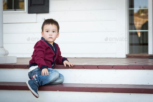 Cute Melancholy Mixed Race Boy Sitting on Front Porch Steps.