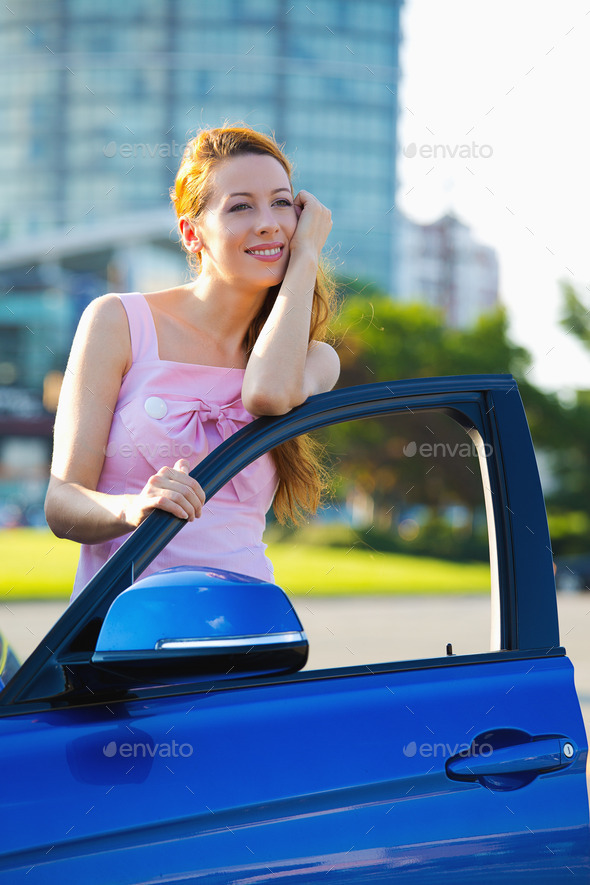 woman standing next to her new blue car