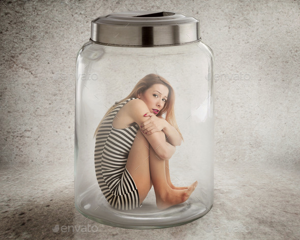 Young lonely woman sitting in glass jar