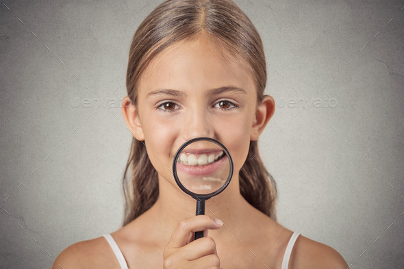 girl showing teeth through a magnifying glass