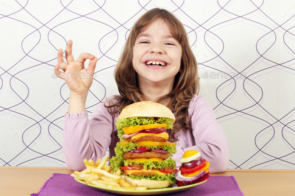 happy little girl with big hamburger and ok hand sign
