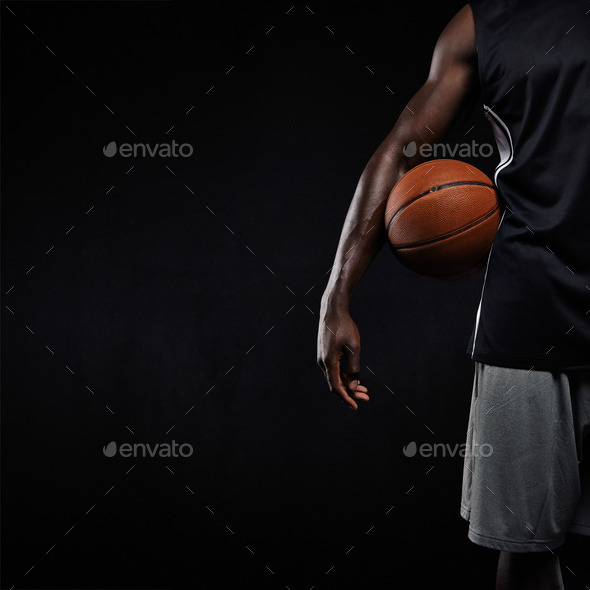 Black basketball player standing with a basket ball