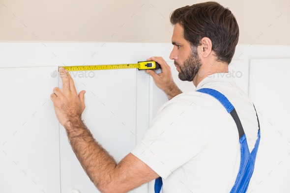 Handyman measuring a wardrobe in a new house (Misc) Photo Download
